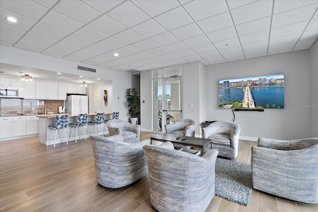 living room featuring a drop ceiling and light hardwood / wood-style floors