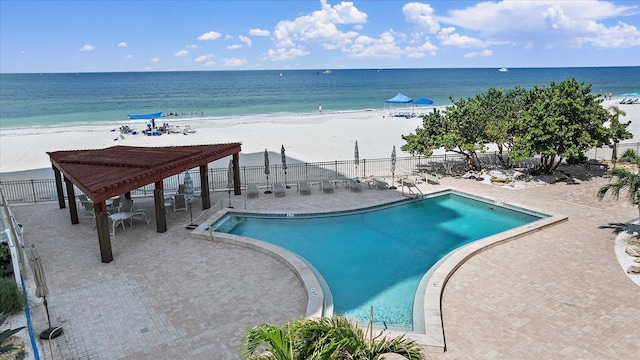 view of swimming pool featuring a view of the beach, a water view, and a patio area