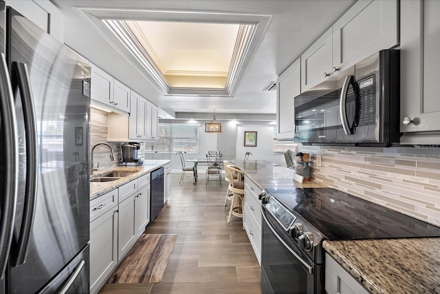 kitchen featuring black appliances, a tray ceiling, light stone countertops, and white cabinets