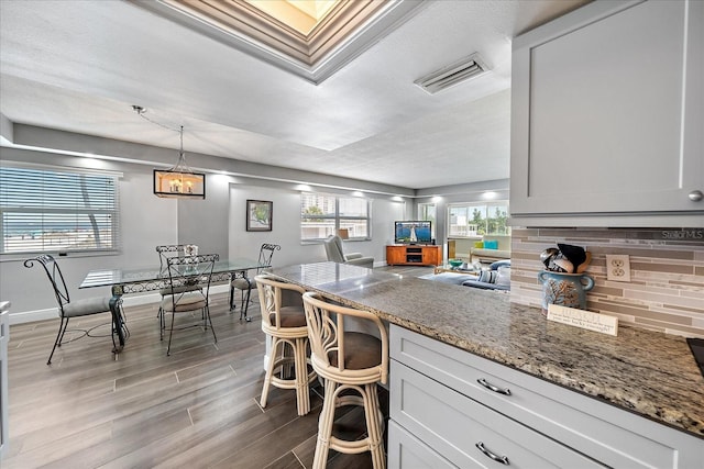 kitchen with white cabinets, light stone counters, and decorative light fixtures