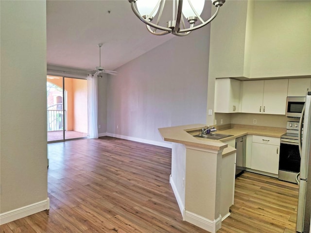 kitchen featuring appliances with stainless steel finishes, hanging light fixtures, kitchen peninsula, light wood-type flooring, and sink