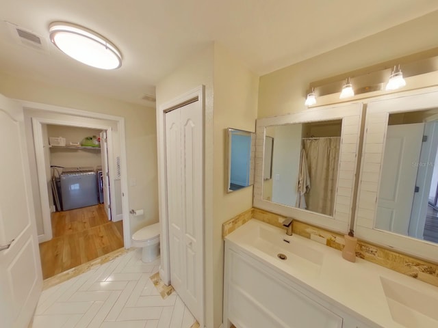 bathroom with hardwood / wood-style floors, vanity, toilet, and washer / dryer