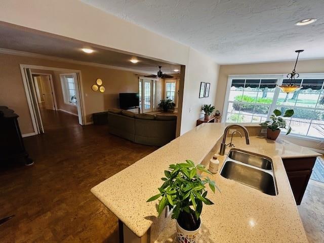 kitchen with light stone countertops, ceiling fan, hanging light fixtures, and sink