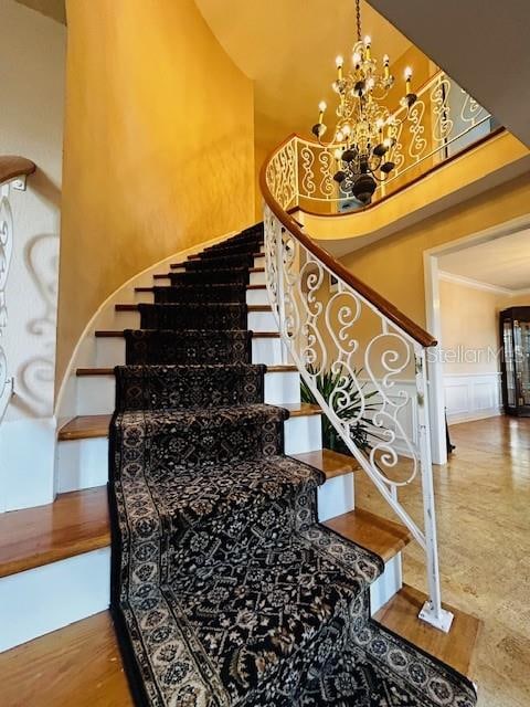 stairs featuring a towering ceiling, crown molding, and a notable chandelier