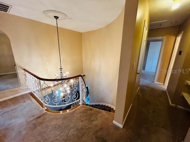 stairway with an inviting chandelier and carpet flooring