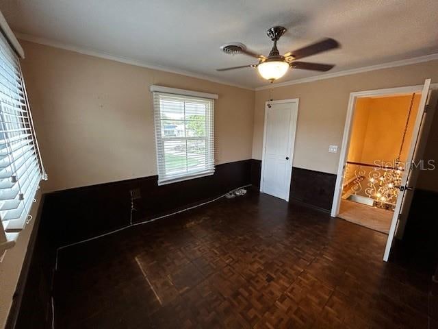 unfurnished room with ceiling fan, dark parquet flooring, and crown molding