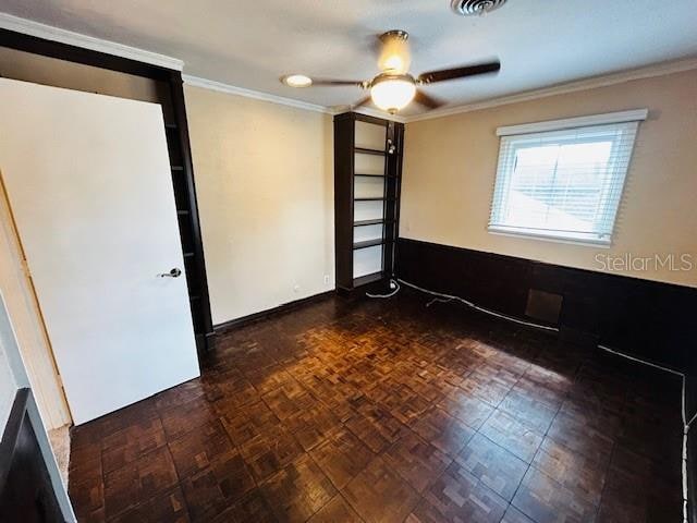 empty room featuring ceiling fan, dark parquet flooring, and ornamental molding