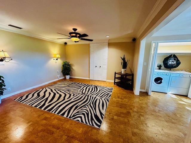 sitting room featuring ceiling fan, ornamental molding, and separate washer and dryer