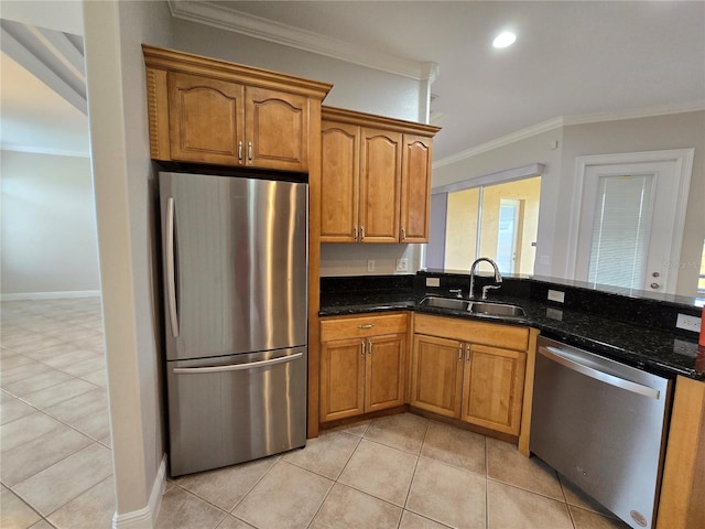 kitchen with dark stone counters, sink, stainless steel appliances, light tile patterned floors, and crown molding