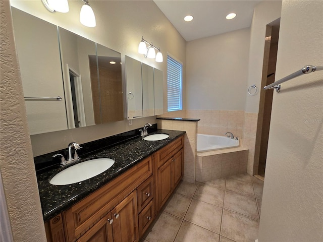 bathroom featuring vanity, tile patterned floors, and a relaxing tiled tub