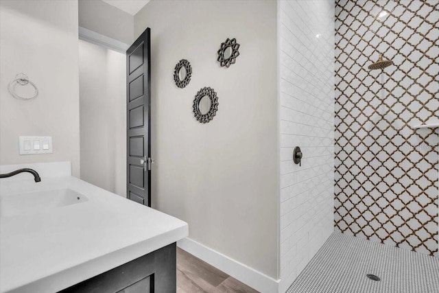 bathroom featuring hardwood / wood-style flooring, vanity, and tiled shower