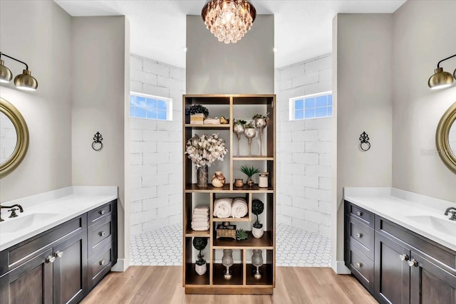 bathroom with wood-type flooring, brick wall, walk in shower, and vanity