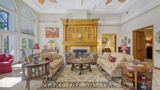 tiled living room featuring french doors, a high ceiling, ceiling fan, and a fireplace