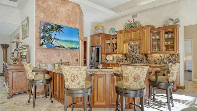 bar featuring stainless steel fridge, backsplash, and light stone counters