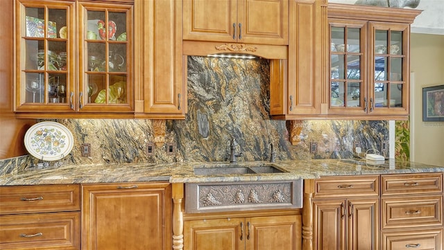 kitchen featuring light stone countertops, sink, and tasteful backsplash