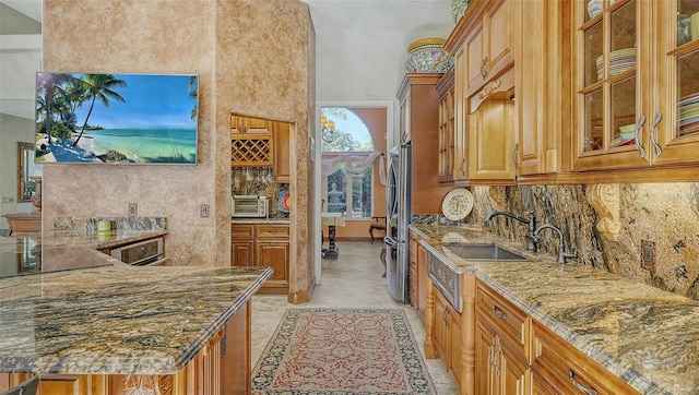 kitchen with light stone counters, sink, stainless steel refrigerator, decorative backsplash, and light tile patterned floors