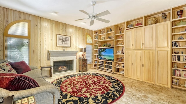 living room with a premium fireplace, a wealth of natural light, wood walls, and ceiling fan