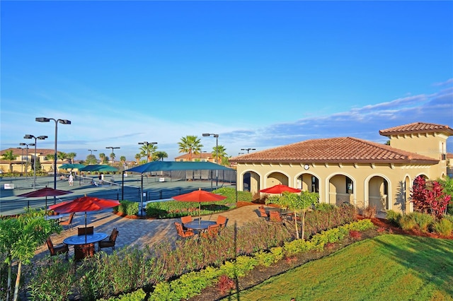 exterior space featuring tennis court and a front lawn