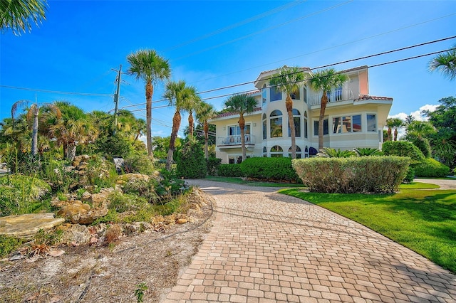 mediterranean / spanish home featuring a balcony and a front lawn