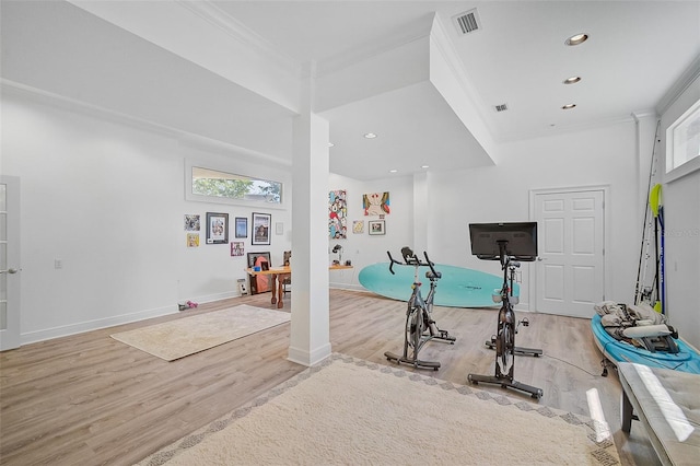 exercise area with ornamental molding and light hardwood / wood-style flooring