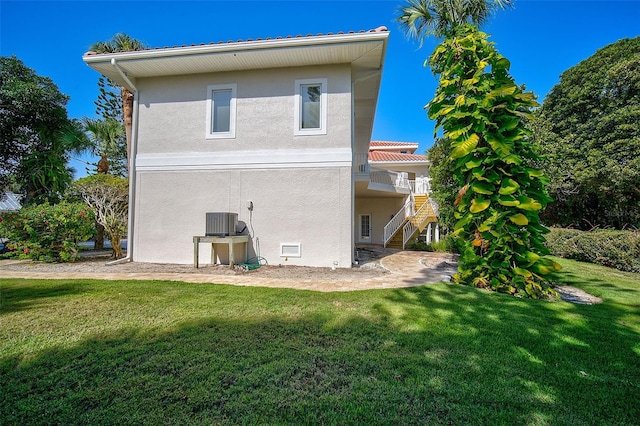 back of property featuring cooling unit and a yard