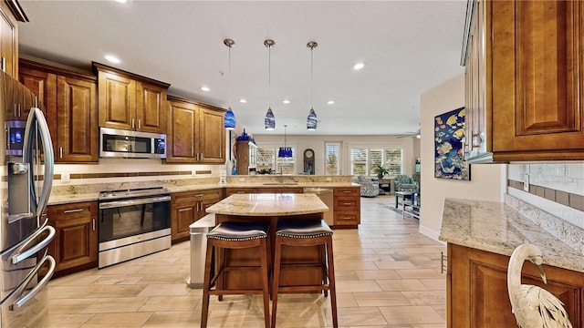 kitchen with hanging light fixtures, kitchen peninsula, a kitchen island, appliances with stainless steel finishes, and a breakfast bar