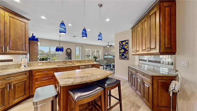 kitchen featuring ceiling fan, pendant lighting, sink, kitchen peninsula, and a kitchen bar