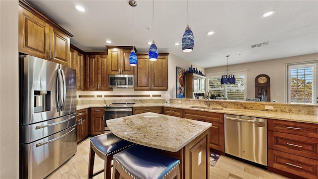 kitchen featuring sink, kitchen peninsula, a kitchen bar, hanging light fixtures, and appliances with stainless steel finishes