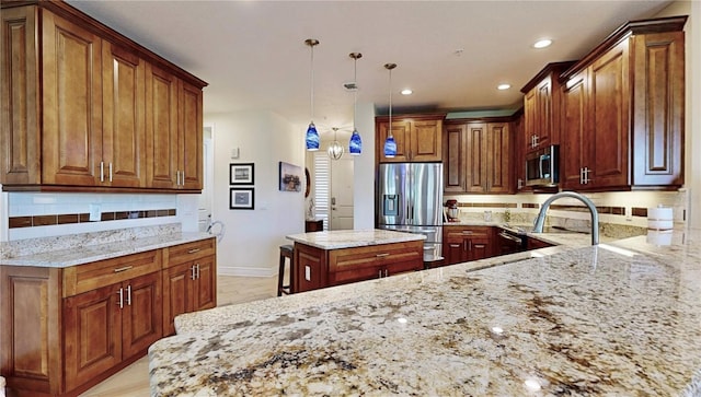 kitchen with pendant lighting, tasteful backsplash, a kitchen island, stainless steel appliances, and light stone countertops