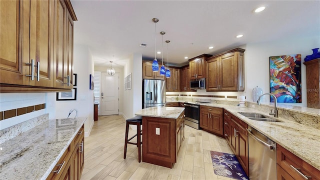 kitchen featuring pendant lighting, sink, appliances with stainless steel finishes, a breakfast bar, and light stone countertops