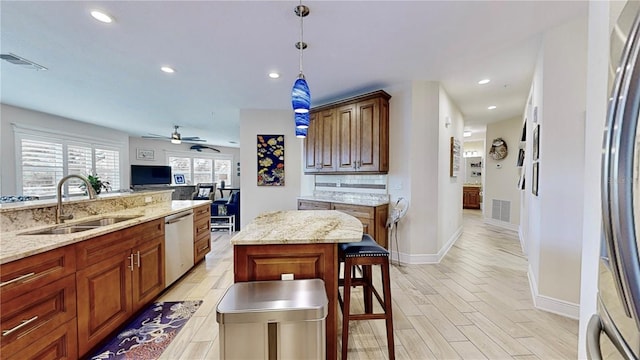 kitchen with dishwasher, light hardwood / wood-style floors, sink, a kitchen island, and ceiling fan