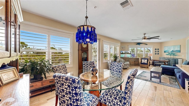 dining area featuring ceiling fan with notable chandelier and light hardwood / wood-style floors