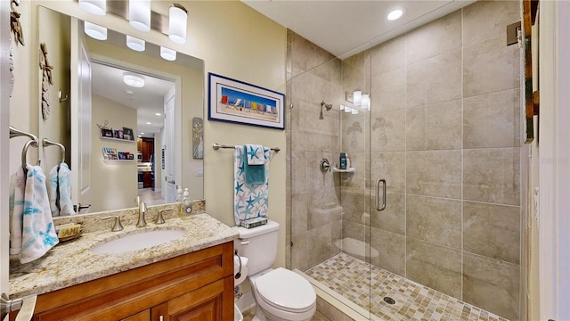 bathroom with a shower with shower door, vanity, and toilet