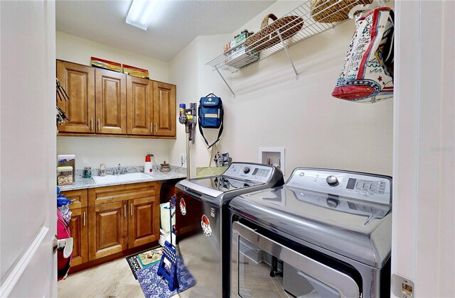 washroom with light wood-type flooring, sink, independent washer and dryer, and cabinets