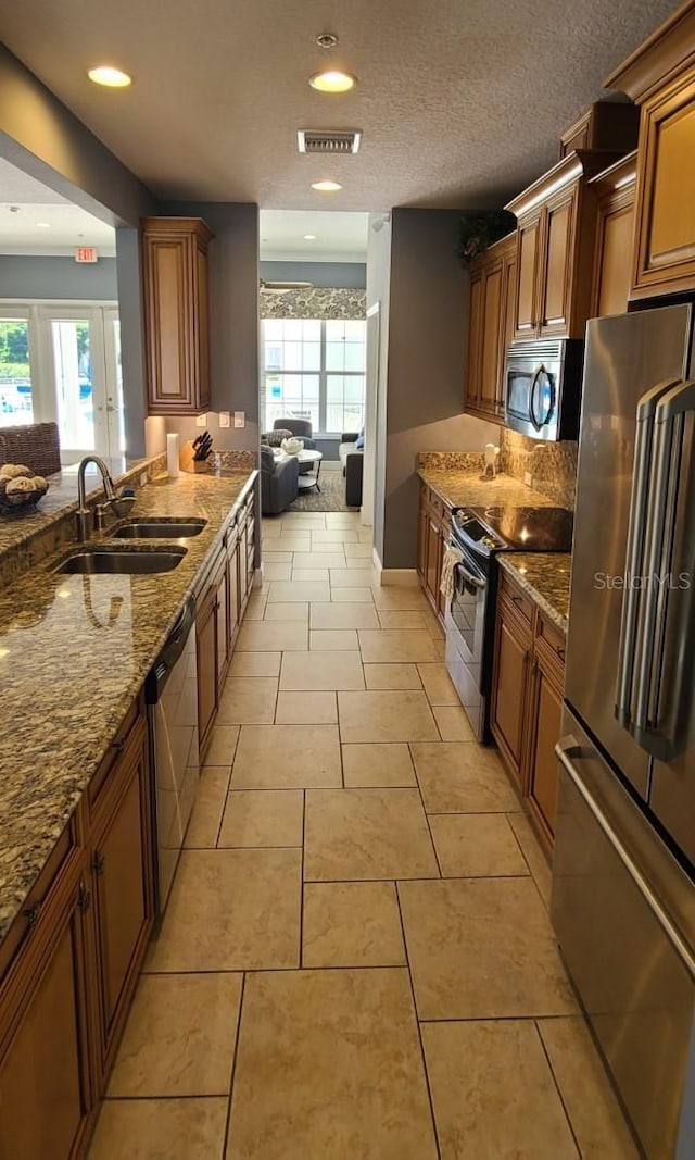 kitchen with light stone counters, stainless steel appliances, plenty of natural light, and sink