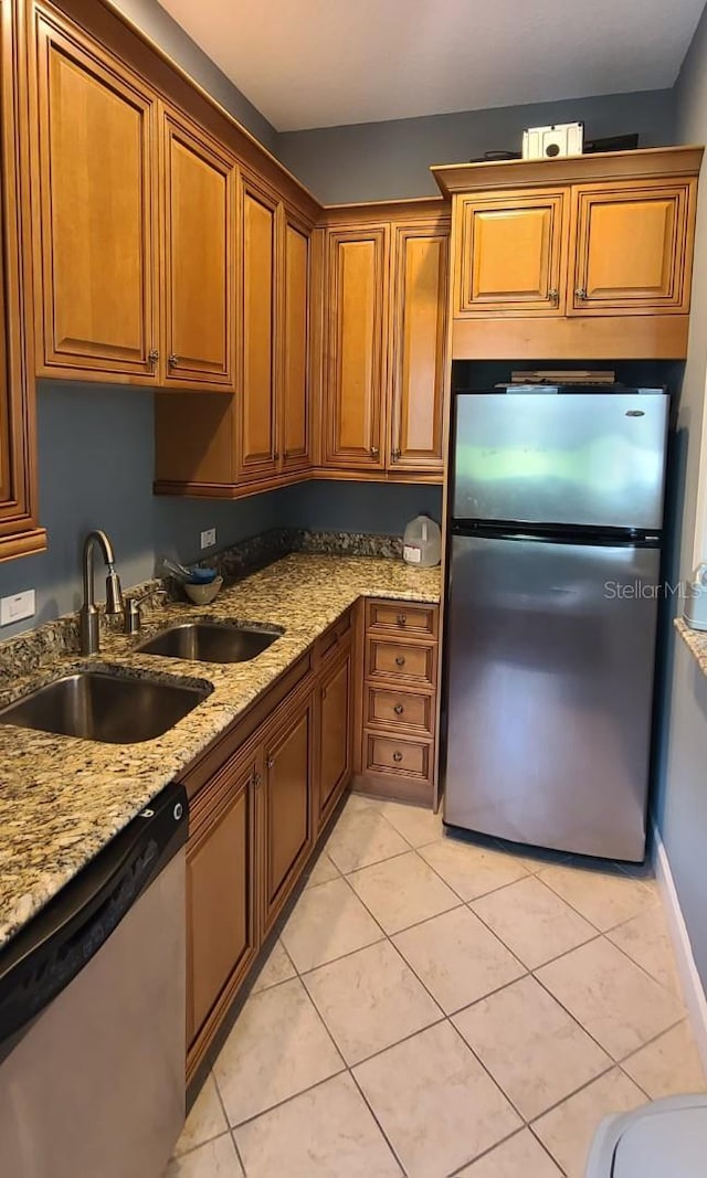 kitchen featuring light stone counters, appliances with stainless steel finishes, light tile patterned floors, and sink