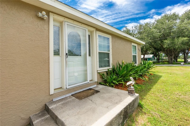 view of exterior entry featuring a yard