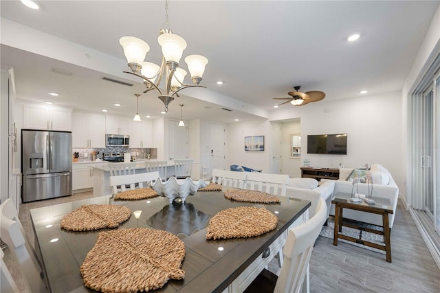 dining area with ceiling fan with notable chandelier and light wood-type flooring