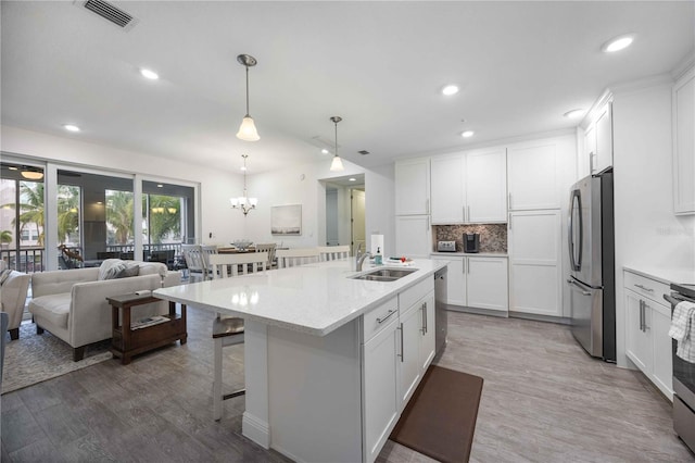 kitchen with a center island with sink, hardwood / wood-style flooring, appliances with stainless steel finishes, and white cabinetry