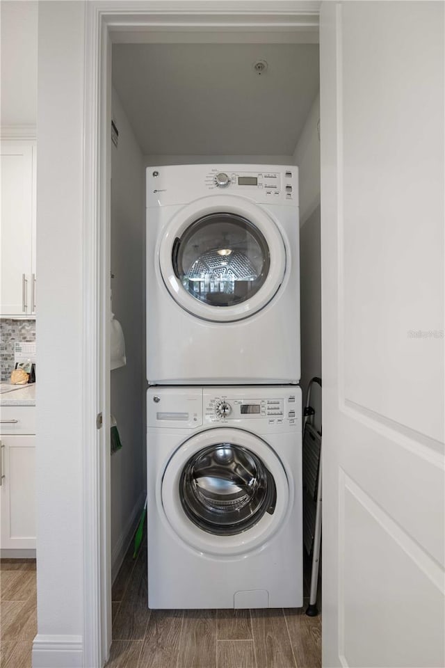 washroom featuring wood-type flooring and stacked washer and dryer