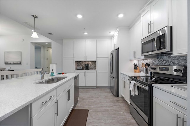 kitchen featuring appliances with stainless steel finishes, hanging light fixtures, light stone counters, and white cabinets