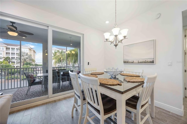 dining area with ceiling fan with notable chandelier and hardwood / wood-style floors