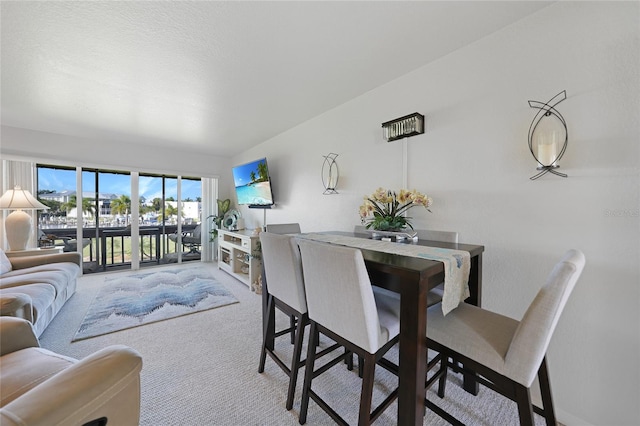 dining room with light carpet and lofted ceiling