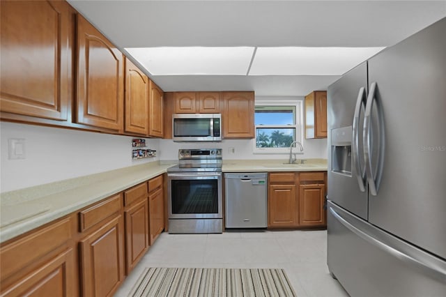 kitchen with stainless steel appliances, light tile patterned flooring, and sink