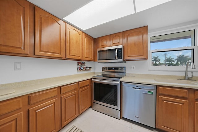 kitchen with appliances with stainless steel finishes, sink, and light tile patterned floors