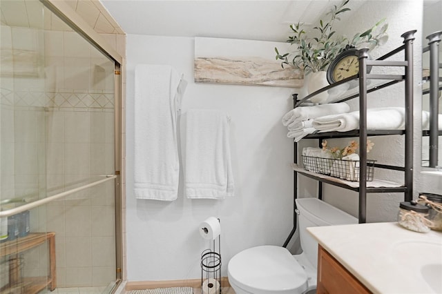 bathroom featuring a shower with shower door, vanity, and toilet