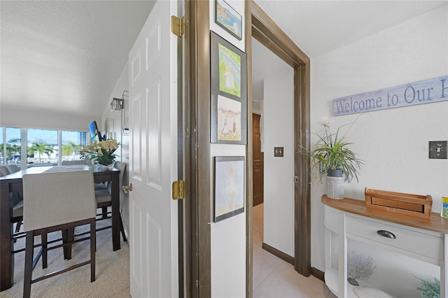 hallway featuring light tile patterned floors and a textured ceiling