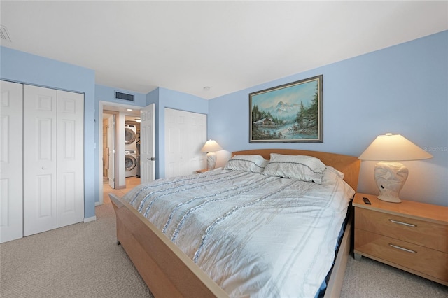 bedroom with light colored carpet, two closets, and stacked washing maching and dryer