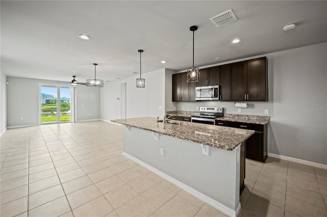 kitchen with dark brown cabinets, light stone countertops, pendant lighting, and stainless steel appliances