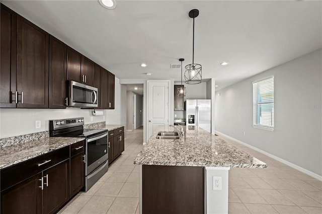 kitchen with light tile patterned flooring, hanging light fixtures, sink, a kitchen island with sink, and stainless steel appliances